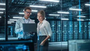 Two employees working side by side, focused on their laptops.