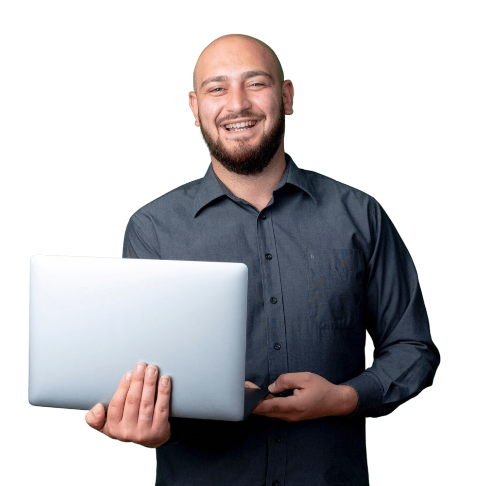 An employee smiling at the camera while holding a laptop.